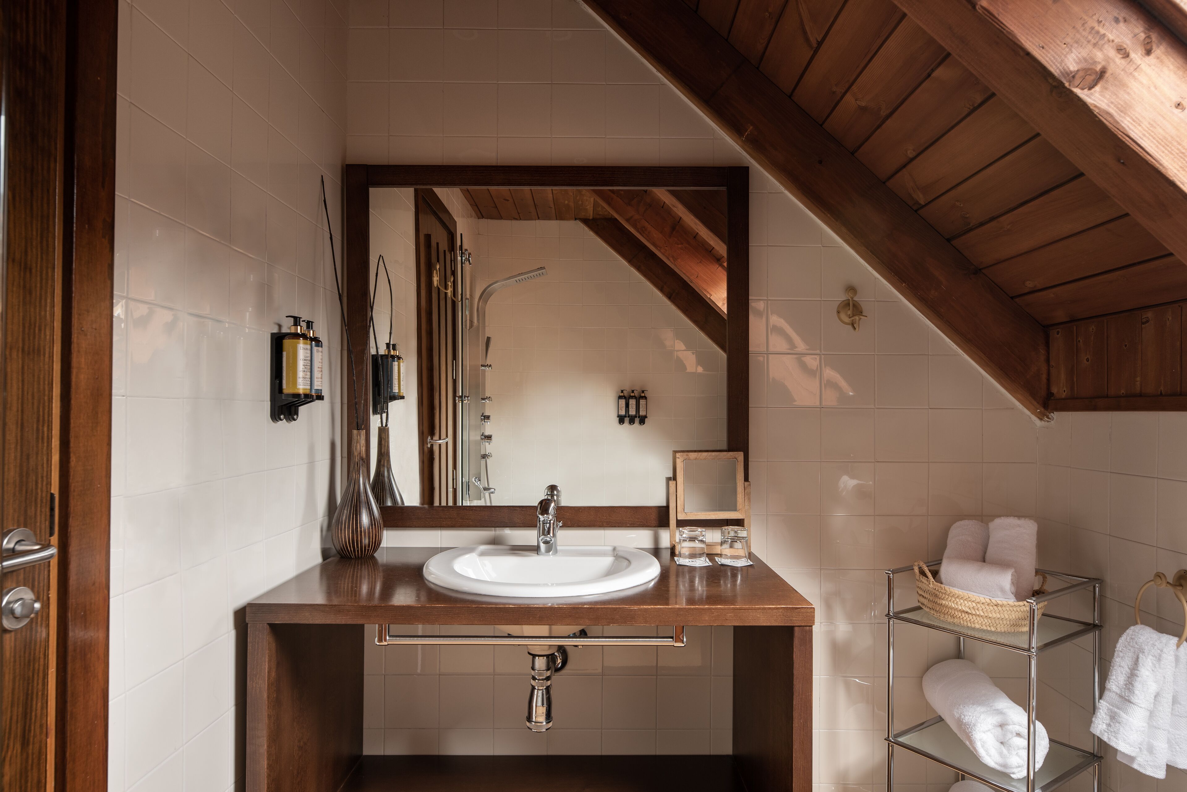 A bathroom with a wooden vanity, a white sink, a mirror, and a towel rack.