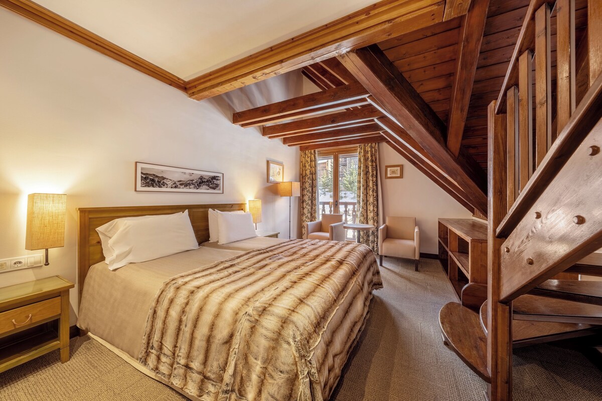 Un dormitorio con una cama de madera, una mesita de noche, un escritorio, una silla y una escalera.