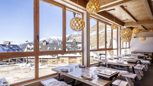 A restaurant with large windows offering a view of snow-covered mountains. Tables are set with white tablecloths and cutlery. - Eurostars La Pleta (Naut Aran)
