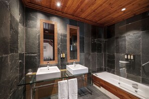Ein modernes Badezimmer mit zwei Waschbecken, einer Glasdusche und einer Holzbalkendecke.
