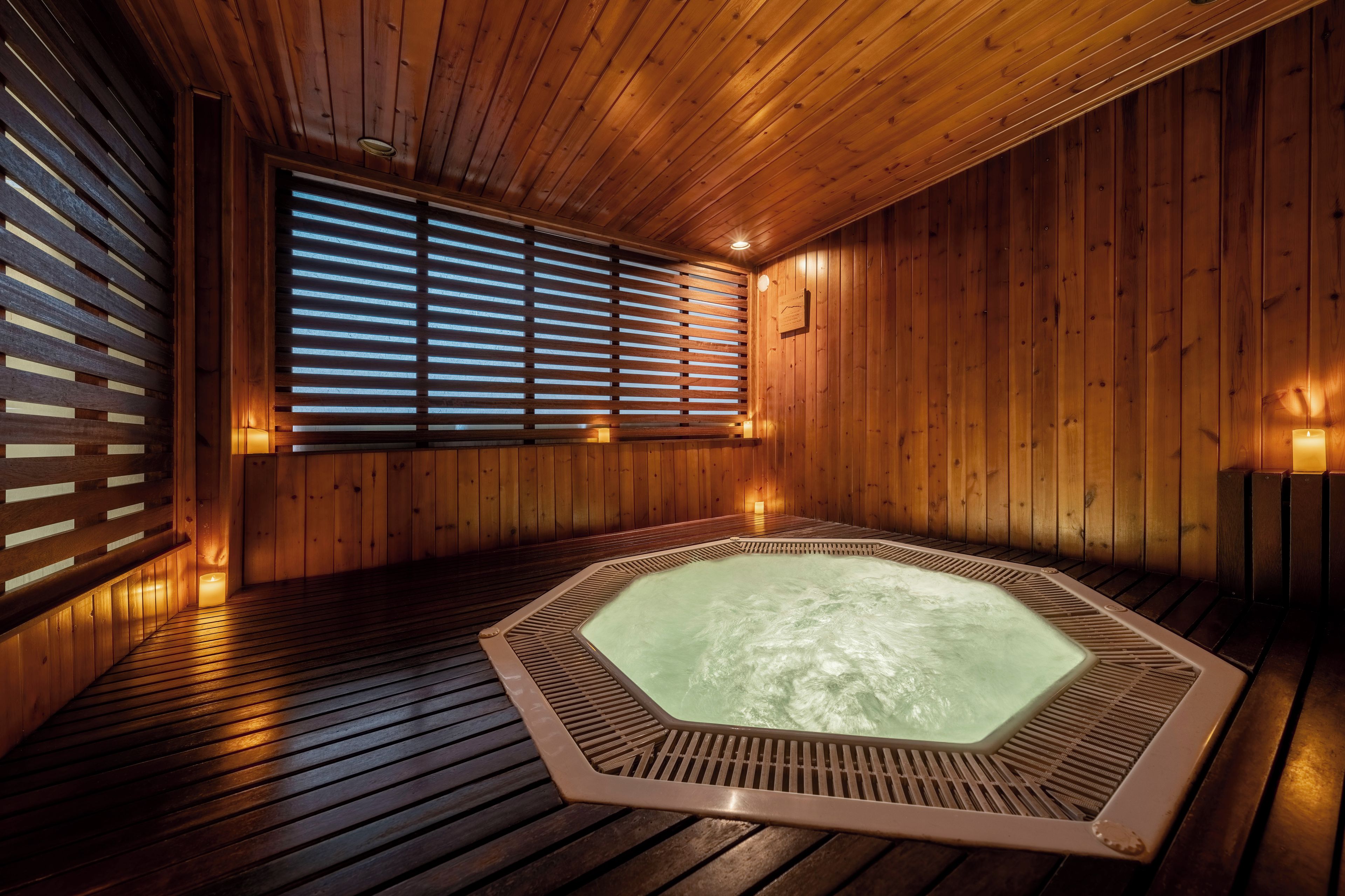 Un sauna de madera con hidromasaje, listones de madera y una ventana con persianas.