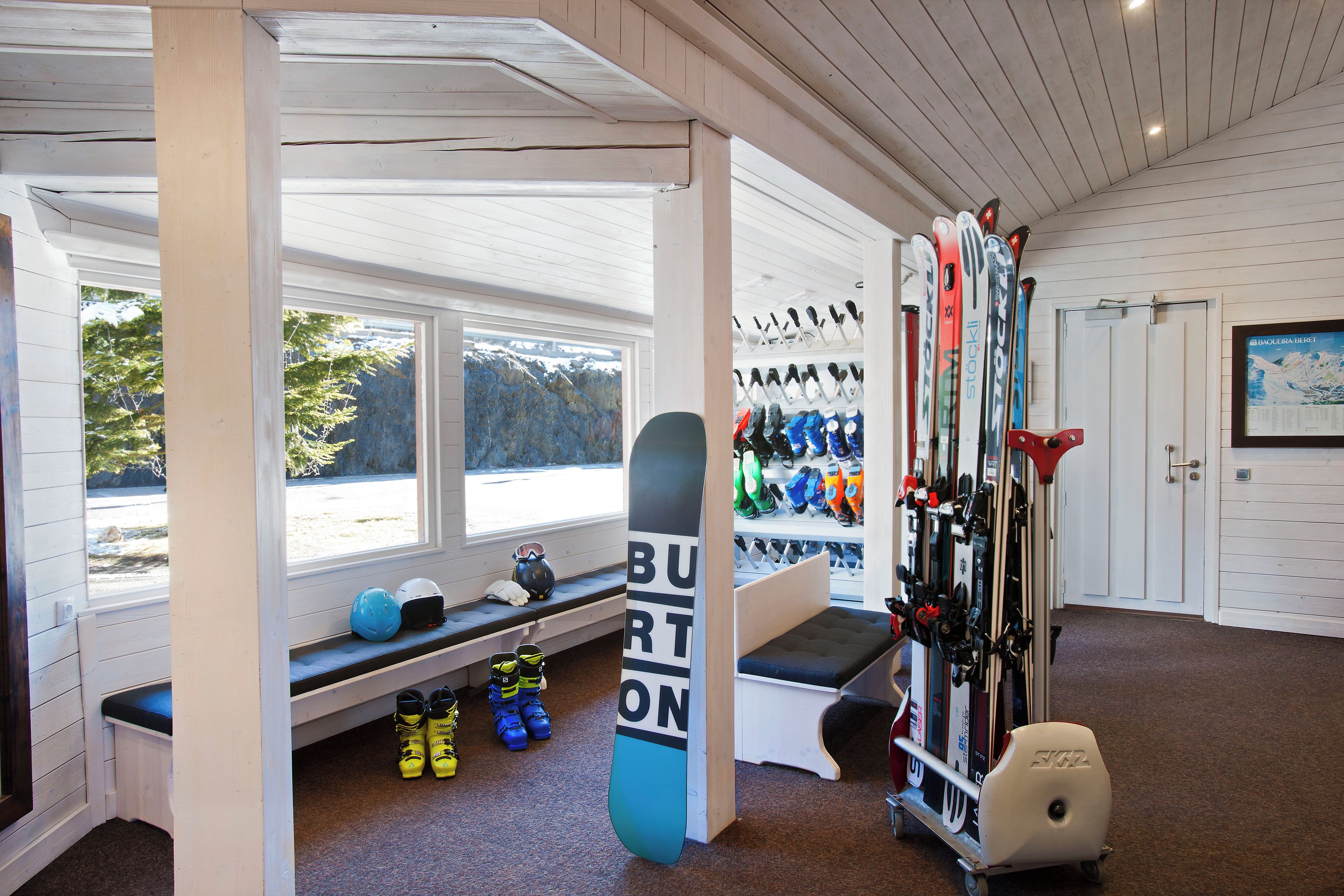 A ski storage room with skis, boots, and helmets.