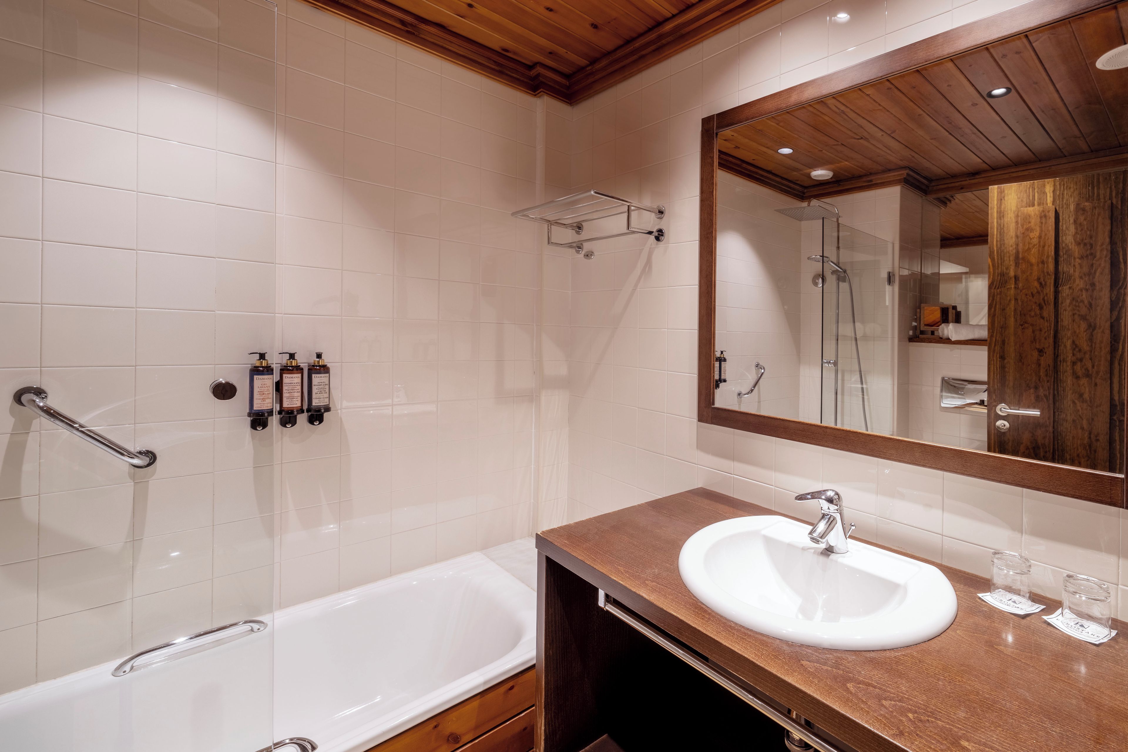 Un baño moderno con una bañera blanca, un tocador de madera, un espejo grande y una zona de ducha.