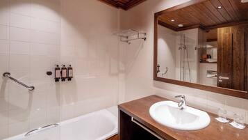 Un baño moderno con una bañera blanca, un tocador de madera, un espejo grande y una zona de ducha.