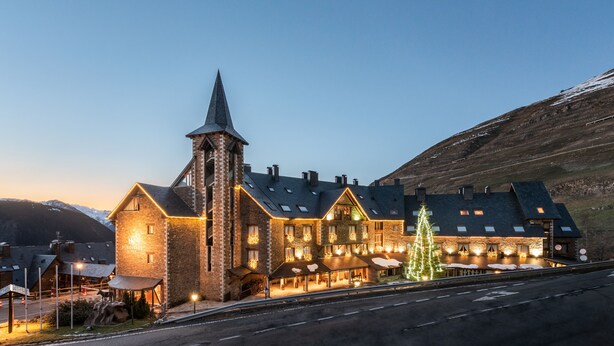 A large, multi-story building with a prominent tower, multiple windows, and a well-lit exterior. - Eurostars La Pleta (Naut Aran)
