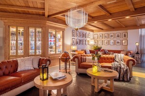 A cozy living room with leather sofas, a wooden coffee table, a globe, and a bookshelf filled with books. - Eurostars La Pleta (Naut Aran)