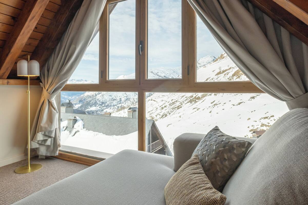 Une chambre avec une grande fenêtre, un lit et une lampe.