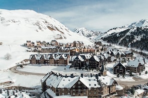 Un pueblo cubierto de nieve en la montaña, con edificios tradicionales de madera y un camino serpenteante.