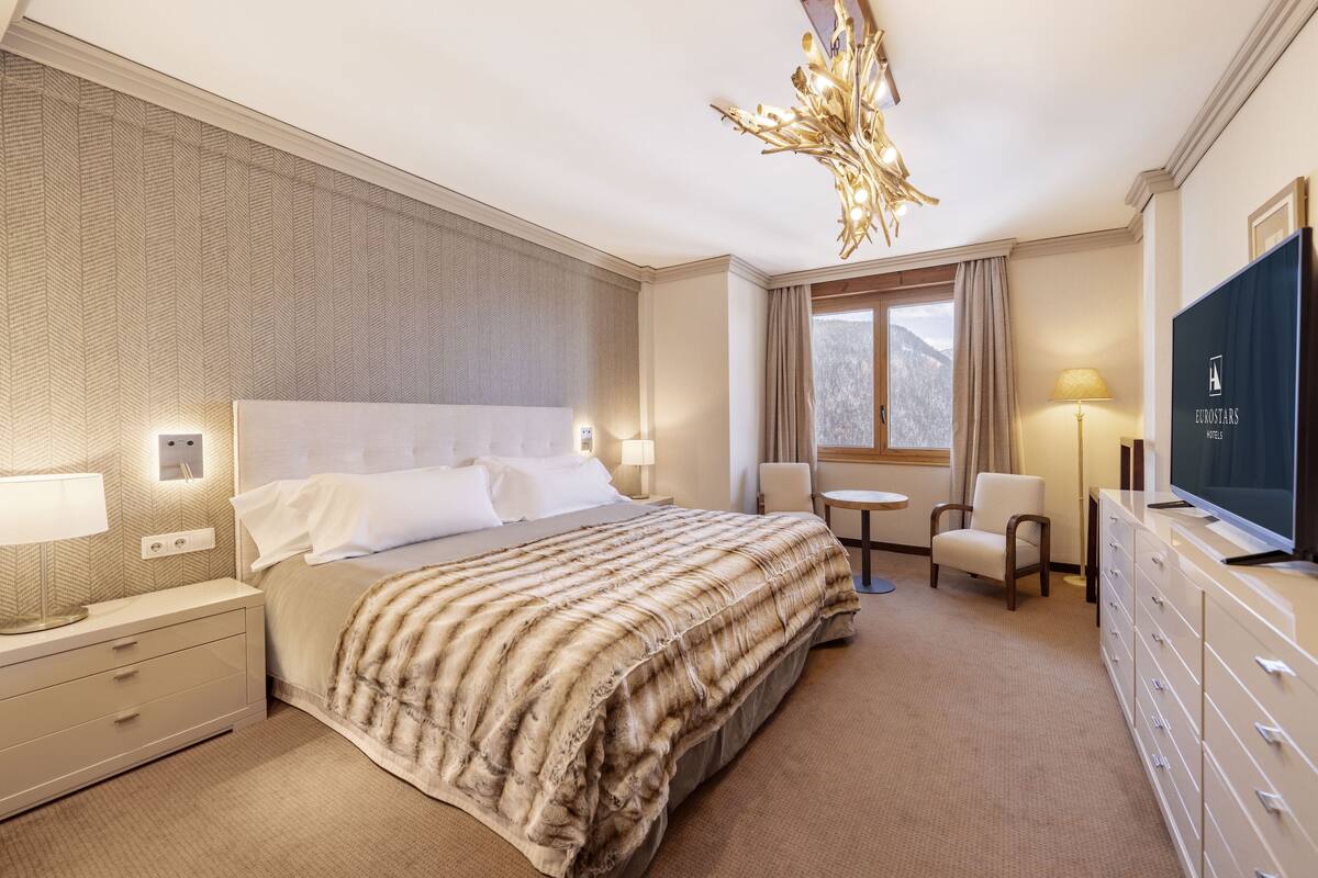 Une chambre d’hôtel avec un grand lit, une télévision, un bureau et une chaise.
