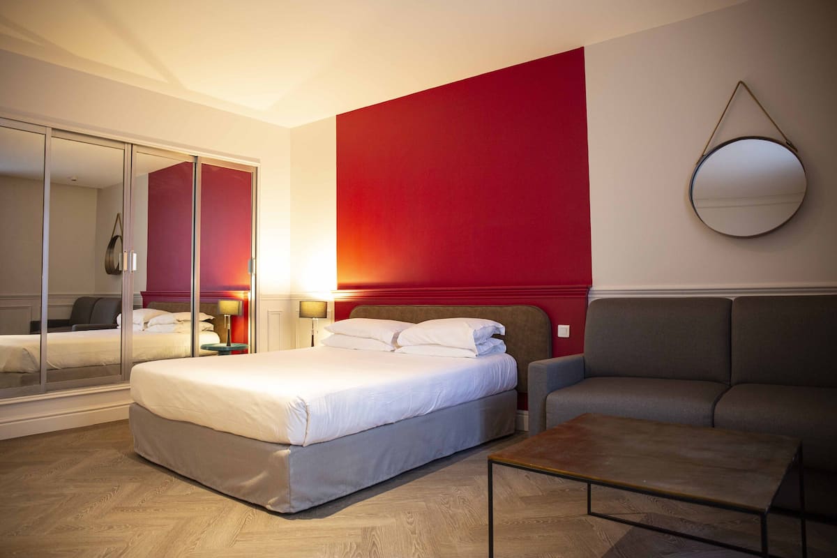 Une chambre d’hôtel moderne équipée d’un lit, d’un canapé, d’une table basse et d’un grand miroir.