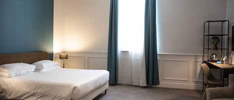 Una habitación de hotel con una cama, un escritorio y una silla.