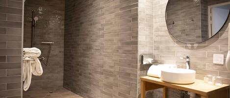 Un baño moderno con ducha, lavamanos y espejo.