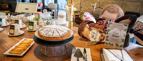 Una mesa con varios pasteles y un pastel, bolsitas de té y un cartel del Hotel Royal.