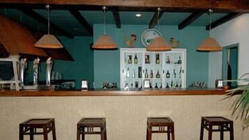 Una zona de bar con taburetes de madera, iluminación colgante y una exhibición de botellas.