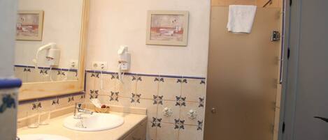 A bathroom with two sinks, a mirror, a towel hanging on the wall, and a shower area.