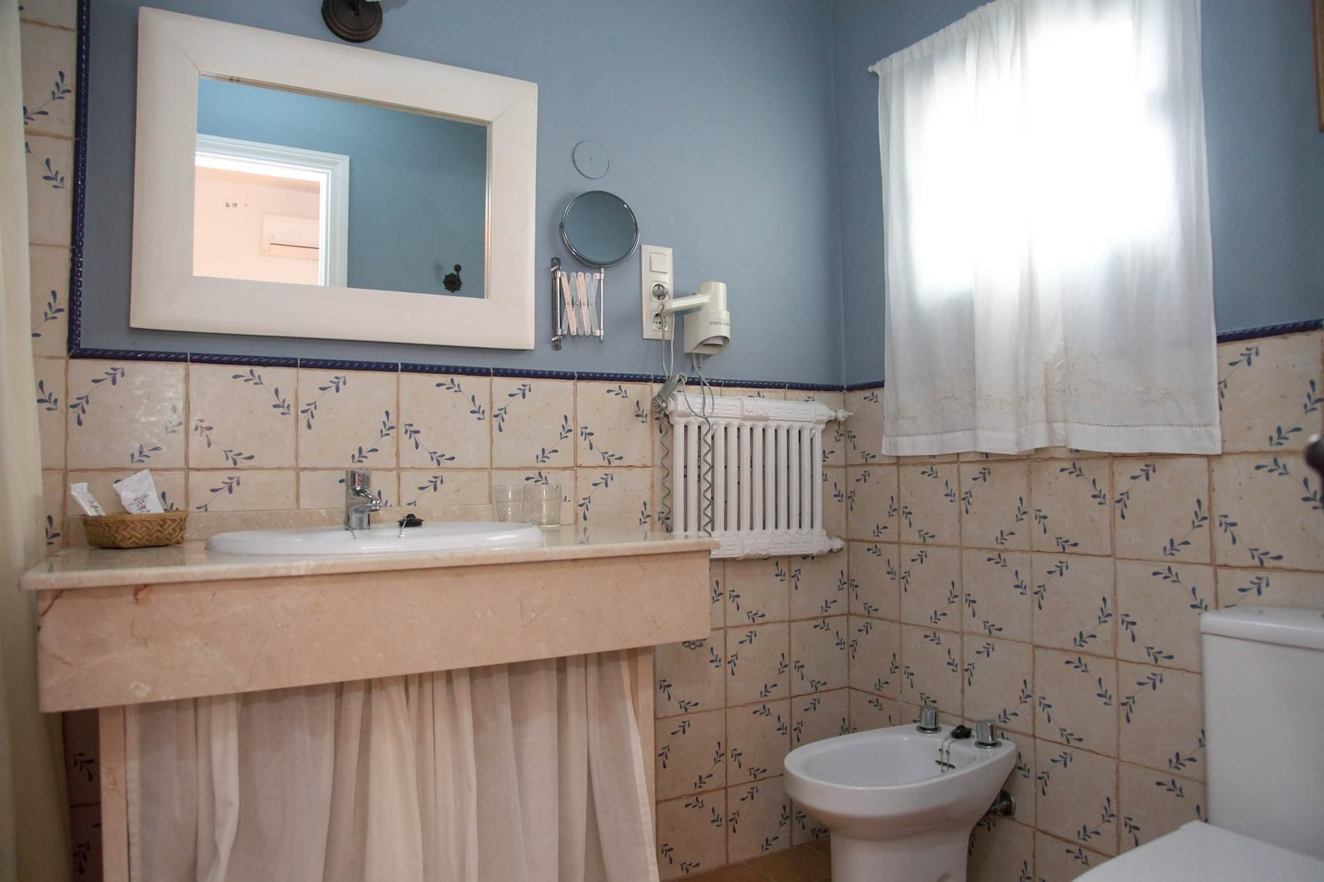 A bathroom with a sink, mirror, towel rack, and a bidet.