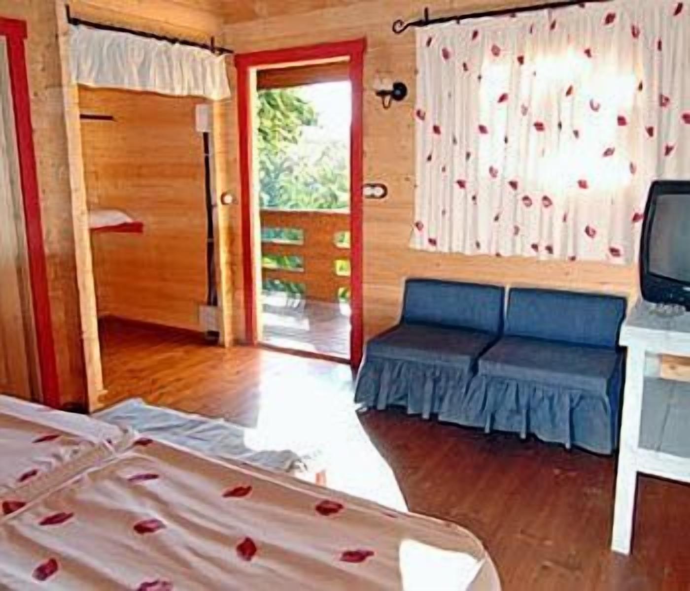 Una stanza con un letto, un'area salotto con televisore e una porta che dà sull'esterno.