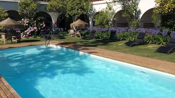 Relax by the serene pool surrounded by lush greenery and comfortable lounge chairs.