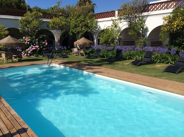 Una piscina al aire libre, sombrillas, tumbonas