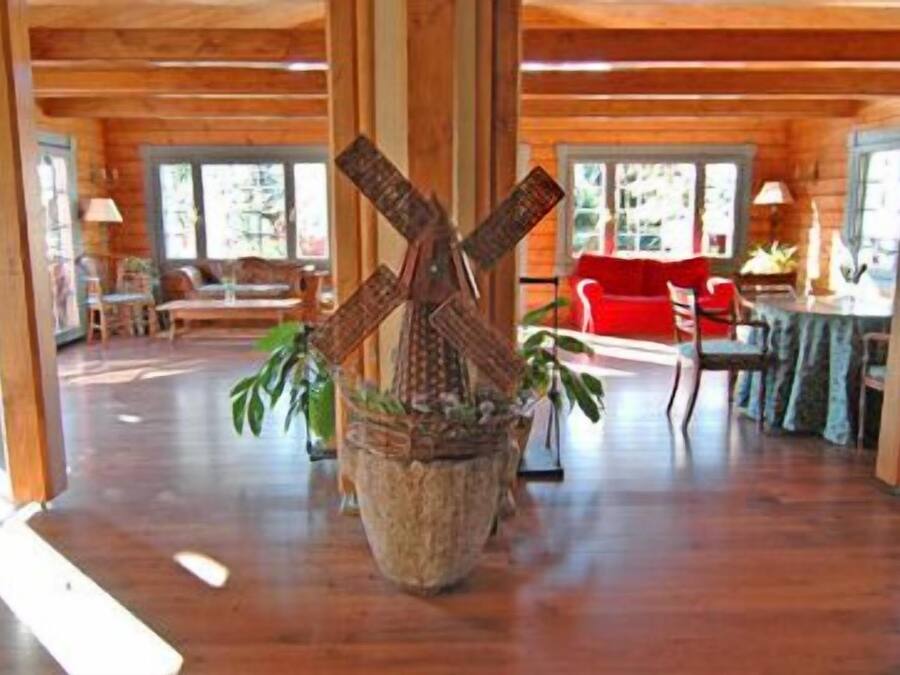 A spacious room with wooden floors, a large wooden beam structure, and a red chair.