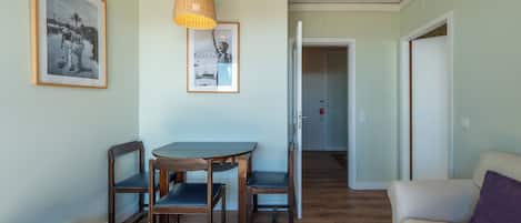 A dining area with a table and chairs, a hanging light fixture, and framed pictures on the wall.