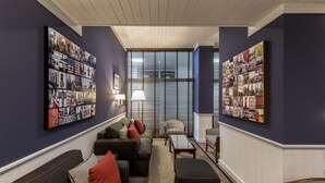 A cozy living room with a sofa, ottoman, and chairs, a coffee table, and two large wall art pieces.