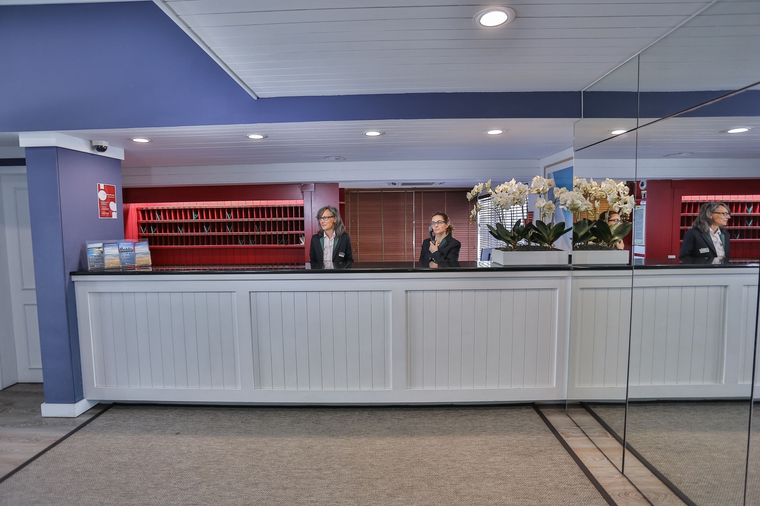 A reception desk with a white panel design, a blue wall, and a red accent wall.