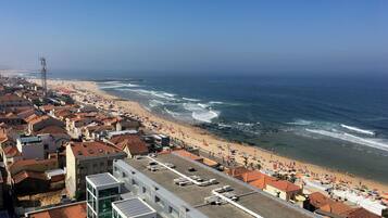 A coastal cityscape with a beach, buildings, and a clear sky.