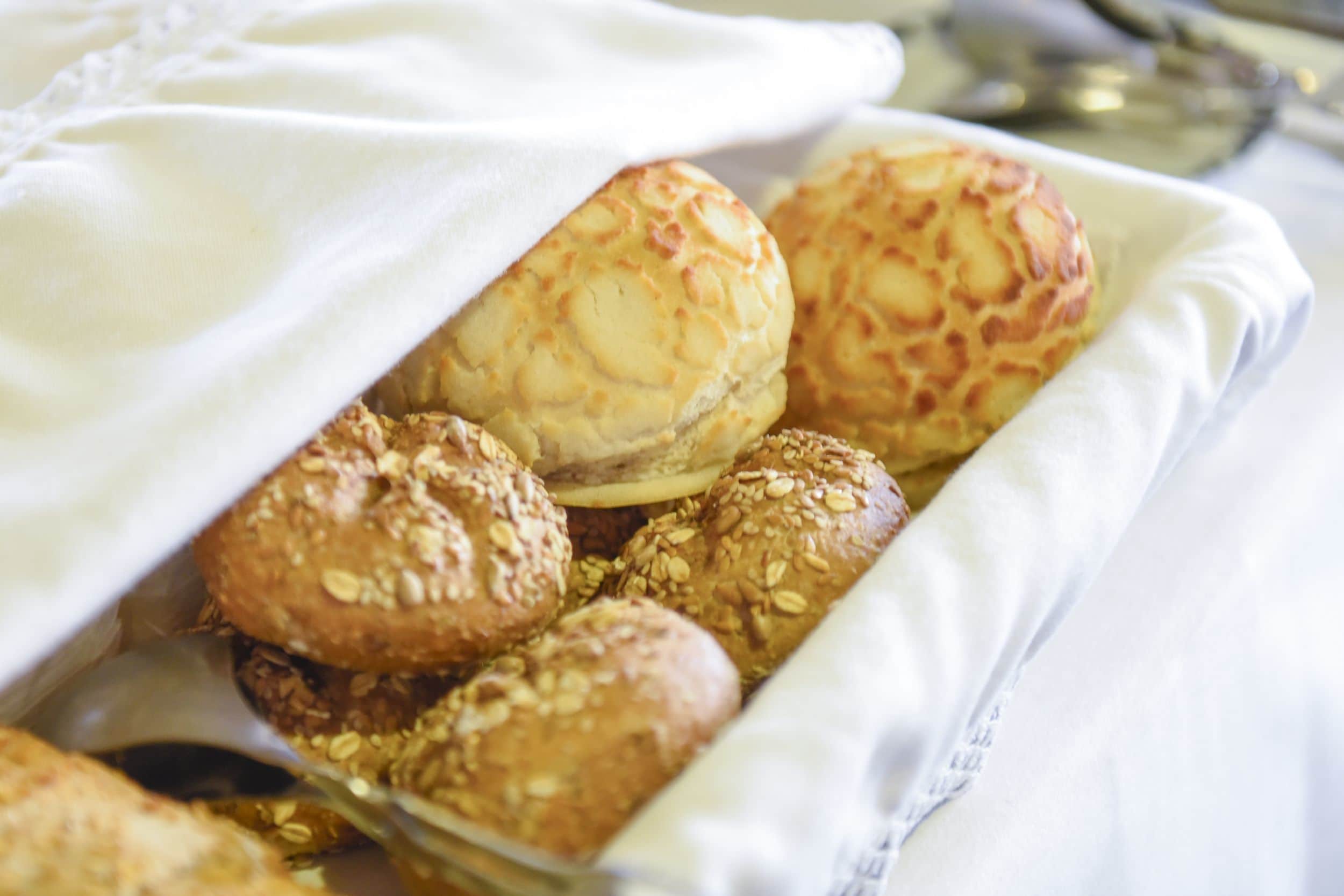 Un plateau rempli de produits de boulangerie, notamment des petits pains et des pâtisseries, posé sur un tissu blanc.