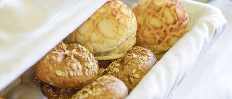 A tray of baked goods, including bread rolls and pastries, on a white cloth.