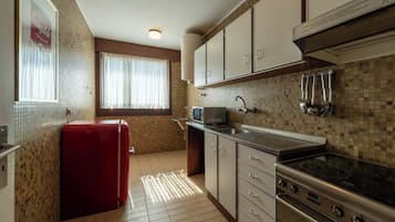 Una cocina compacta con refrigerador, estufa, microondas y salpicadero de azulejos.