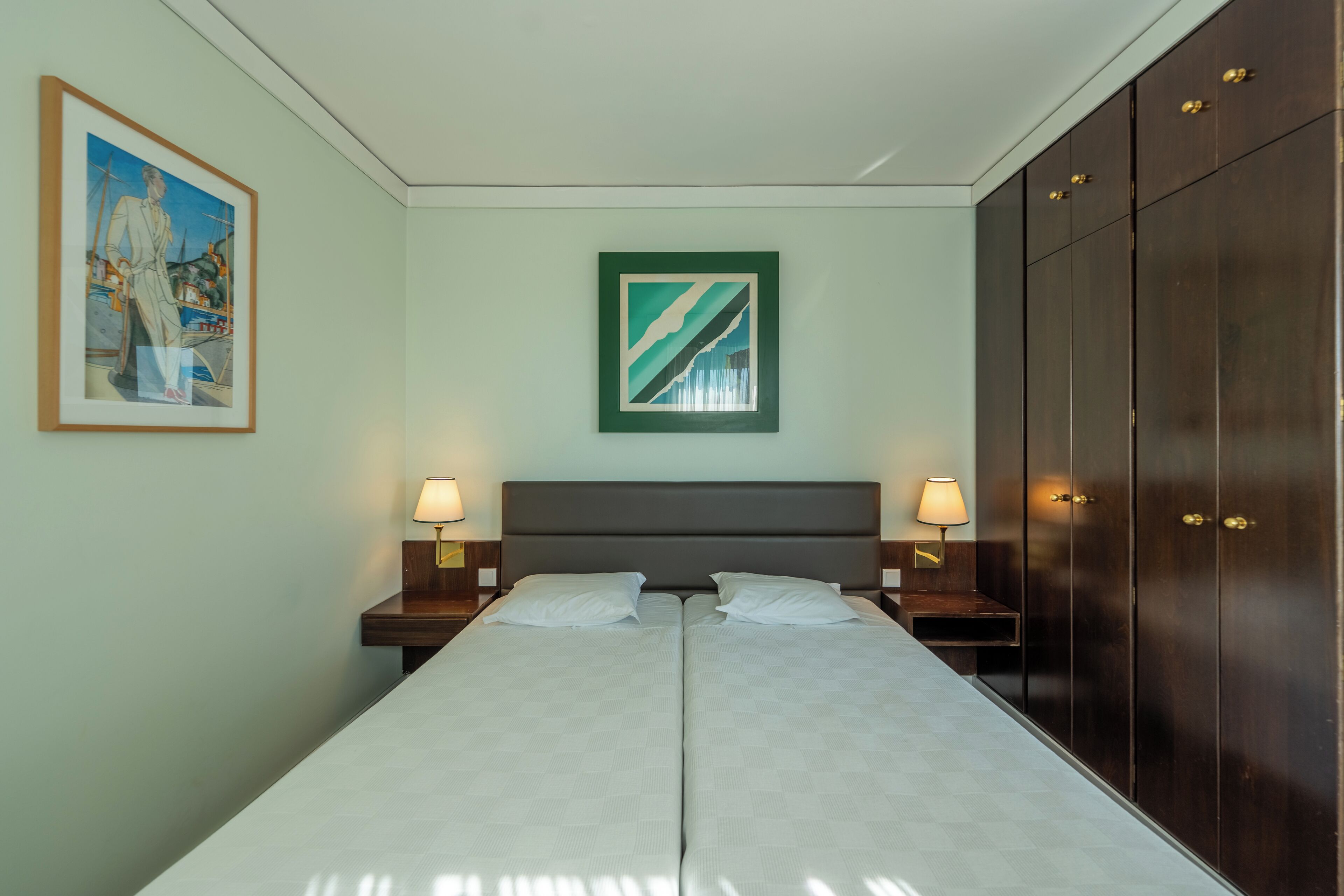 Uma cama de casal com duas mesas de cabeceira, cabeceira e guarda-roupa.