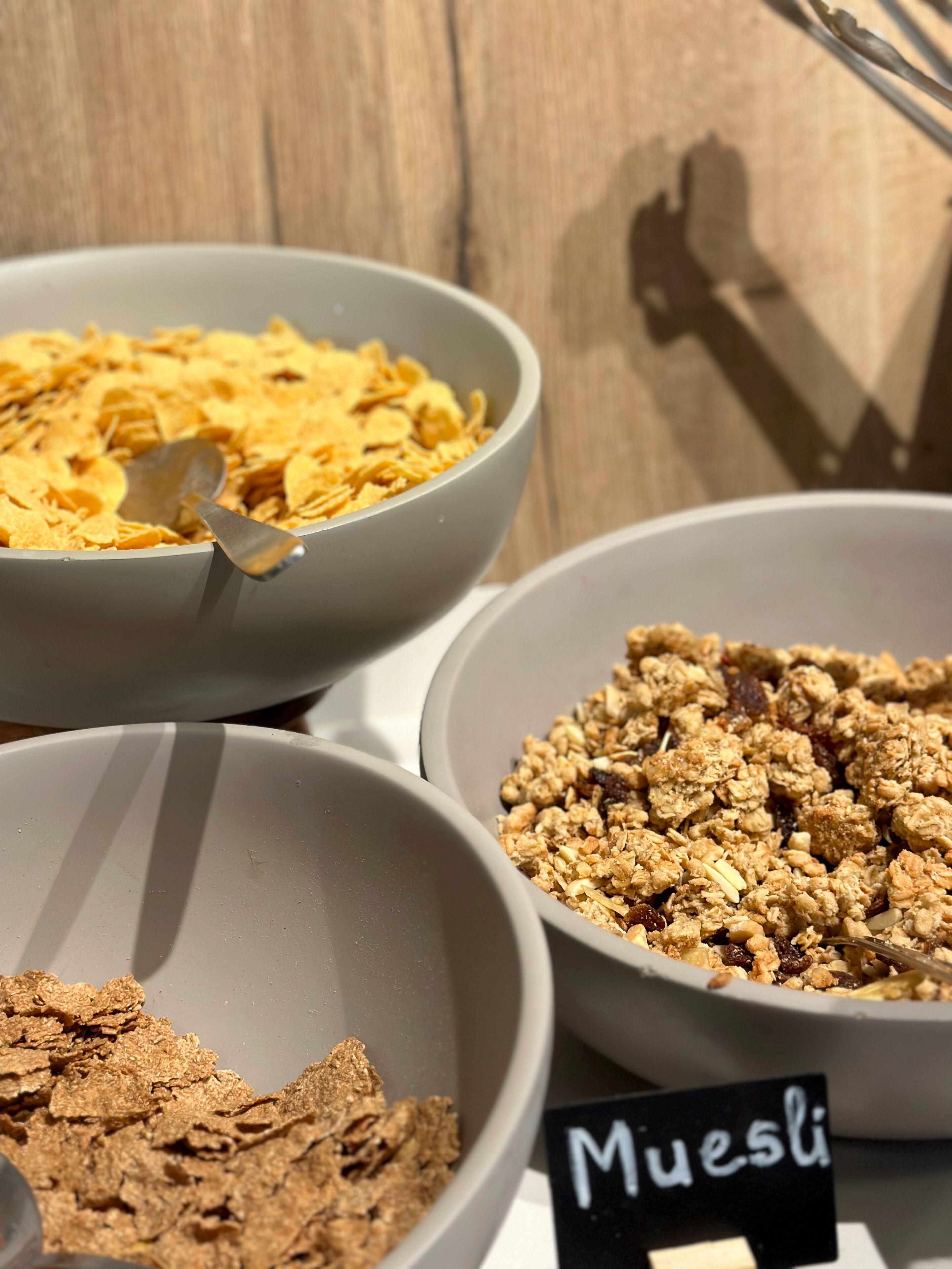 Three bowls of different cereal types on a table.