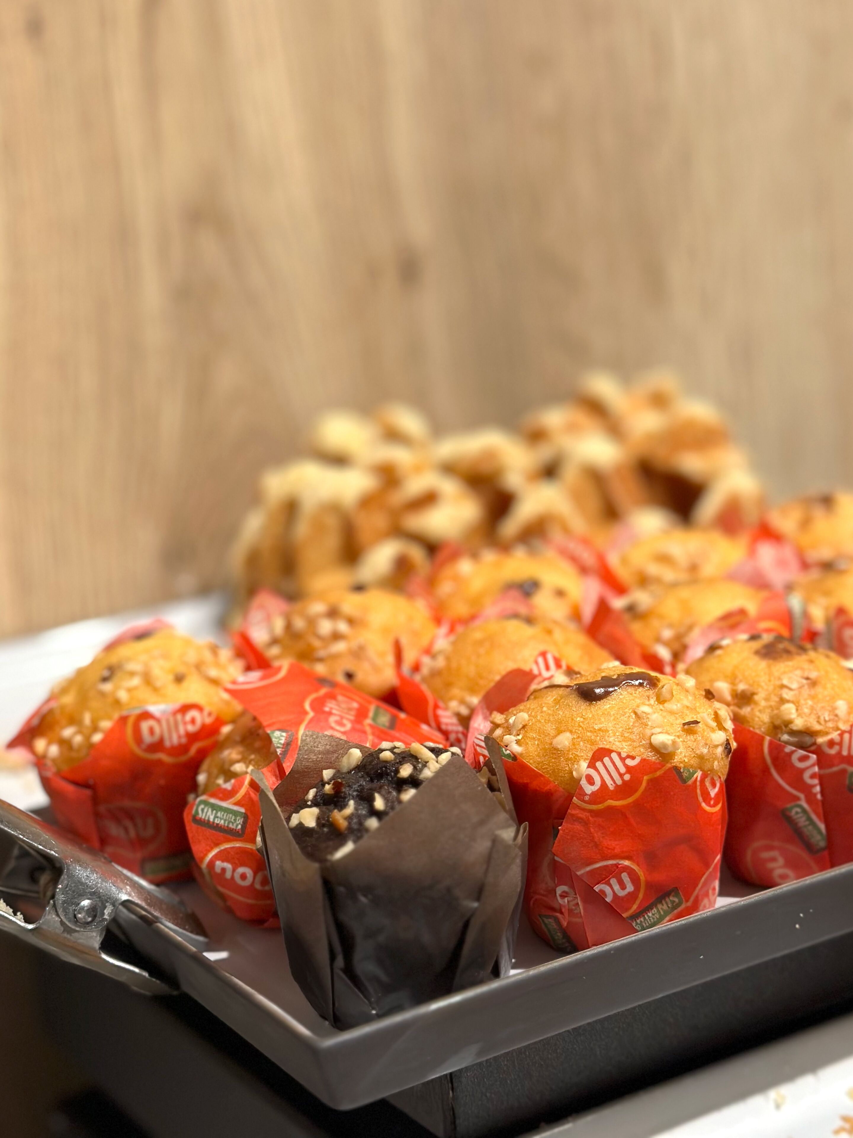 Una bandeja de muffins en envoltorios rojos, algunos con chispas de chocolate y nueces.