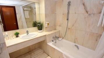 Un baño con lavamanos de mármol, bañera y ducha.
