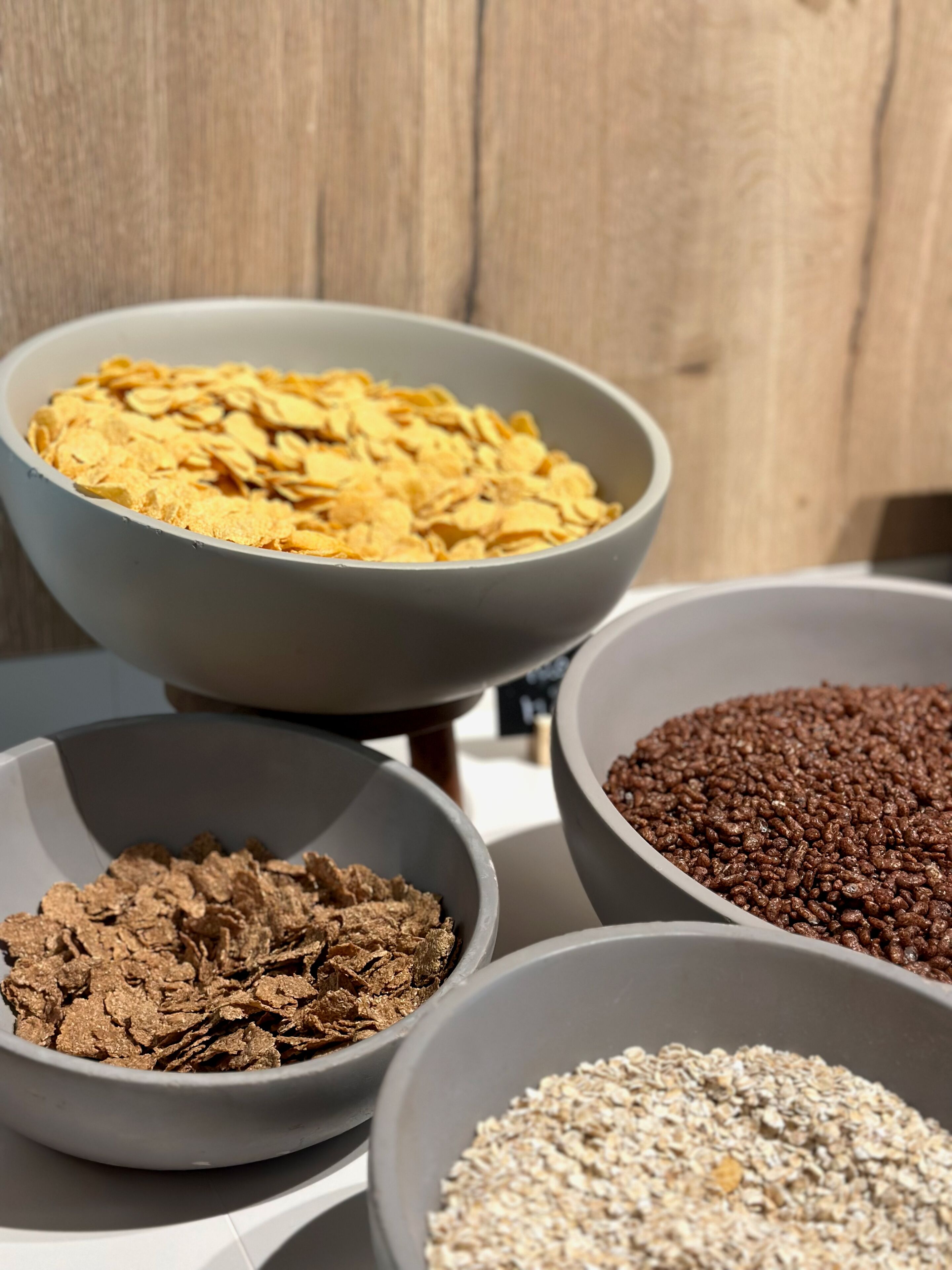 Four bowls of different cereal flakes on a table.