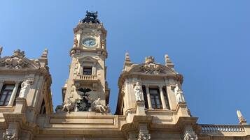 Un edificio histórico con arquitectura ornamentada, que incluye una torre del reloj y estatuas.