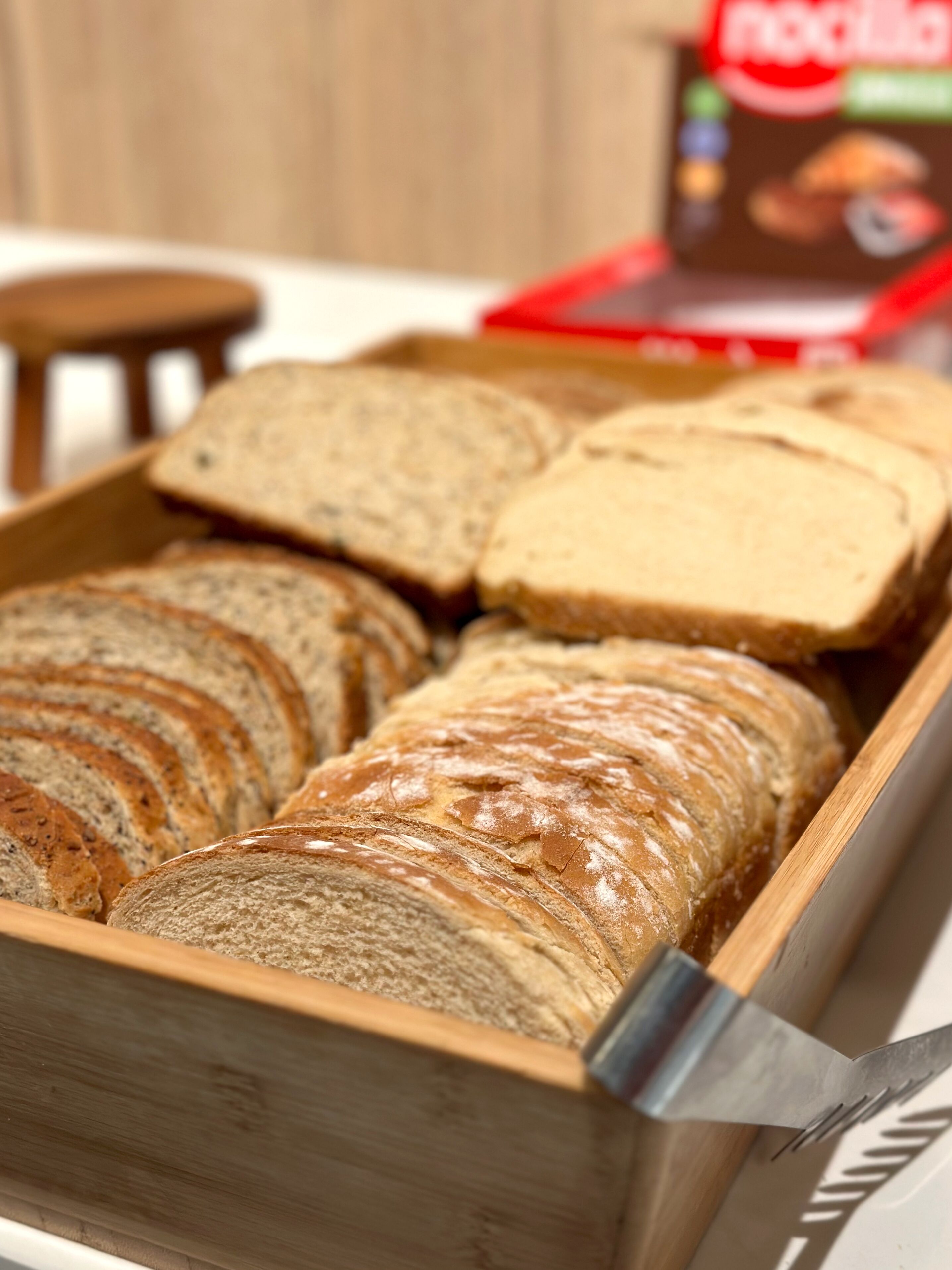Een houten broodkist met verschillende soorten brood.