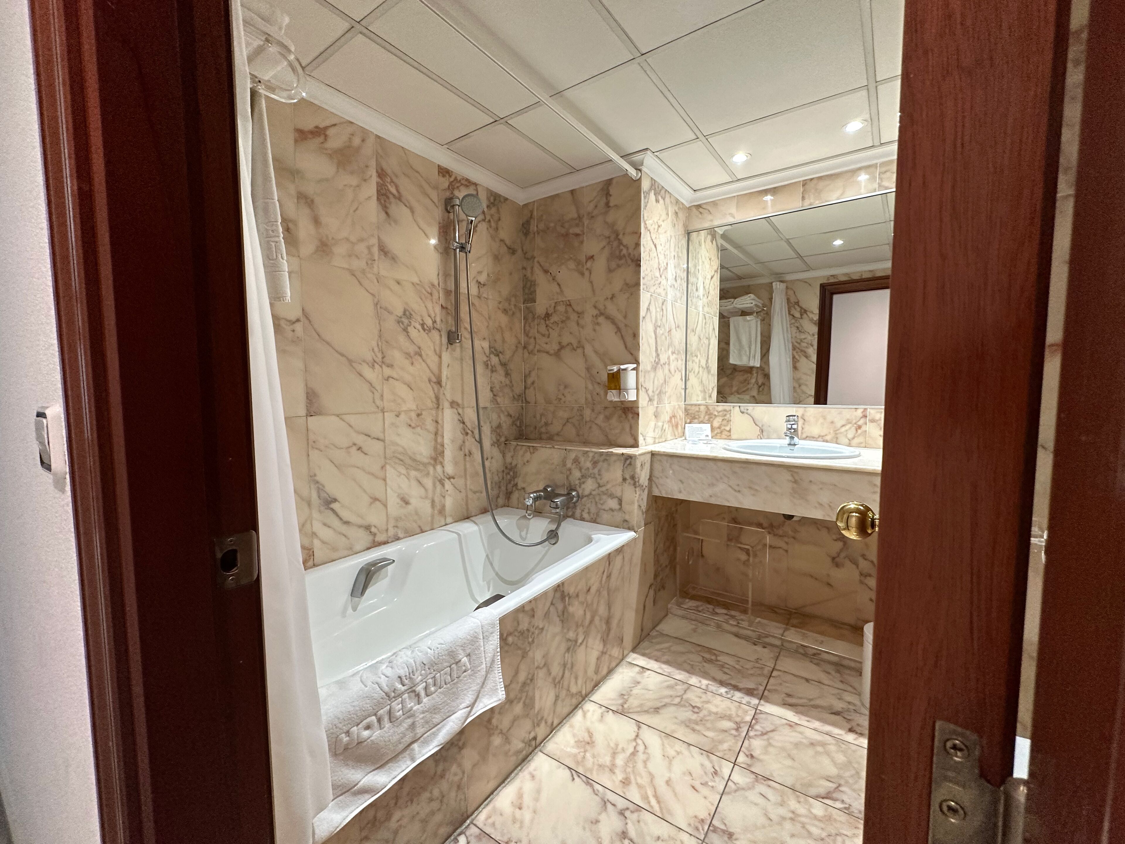 Un baño con suelo de mármol, bañera, ducha y lavabo.