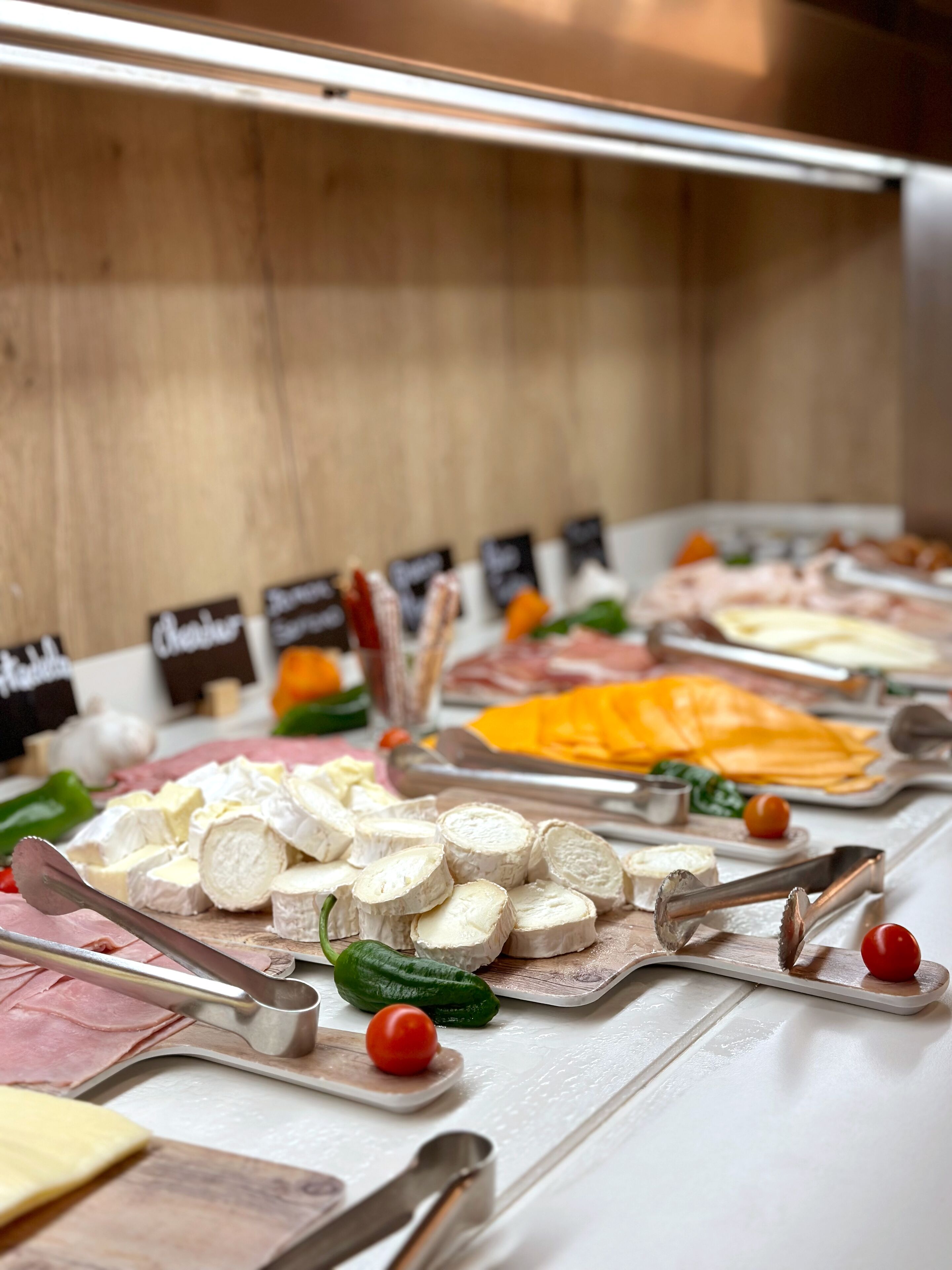 Un bufé con diversos quesos, carnes y verduras.