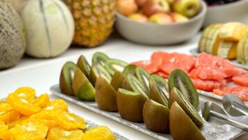 Una variedad de frutas como piña, melón, manzanas y kiwis dispuestas en una bandeja.