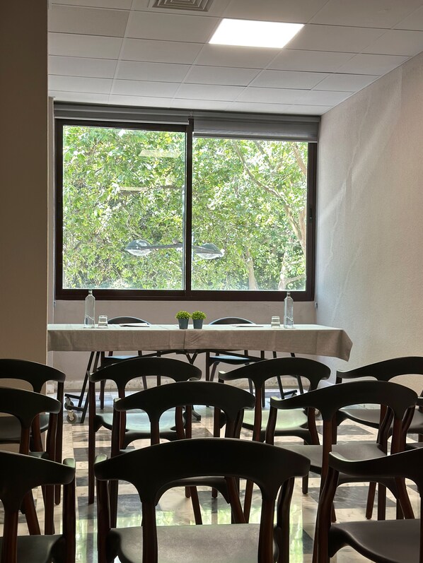 A dining area with a table set for four, chairs, a window with a view of trees, and a ceiling with recessed lighting.