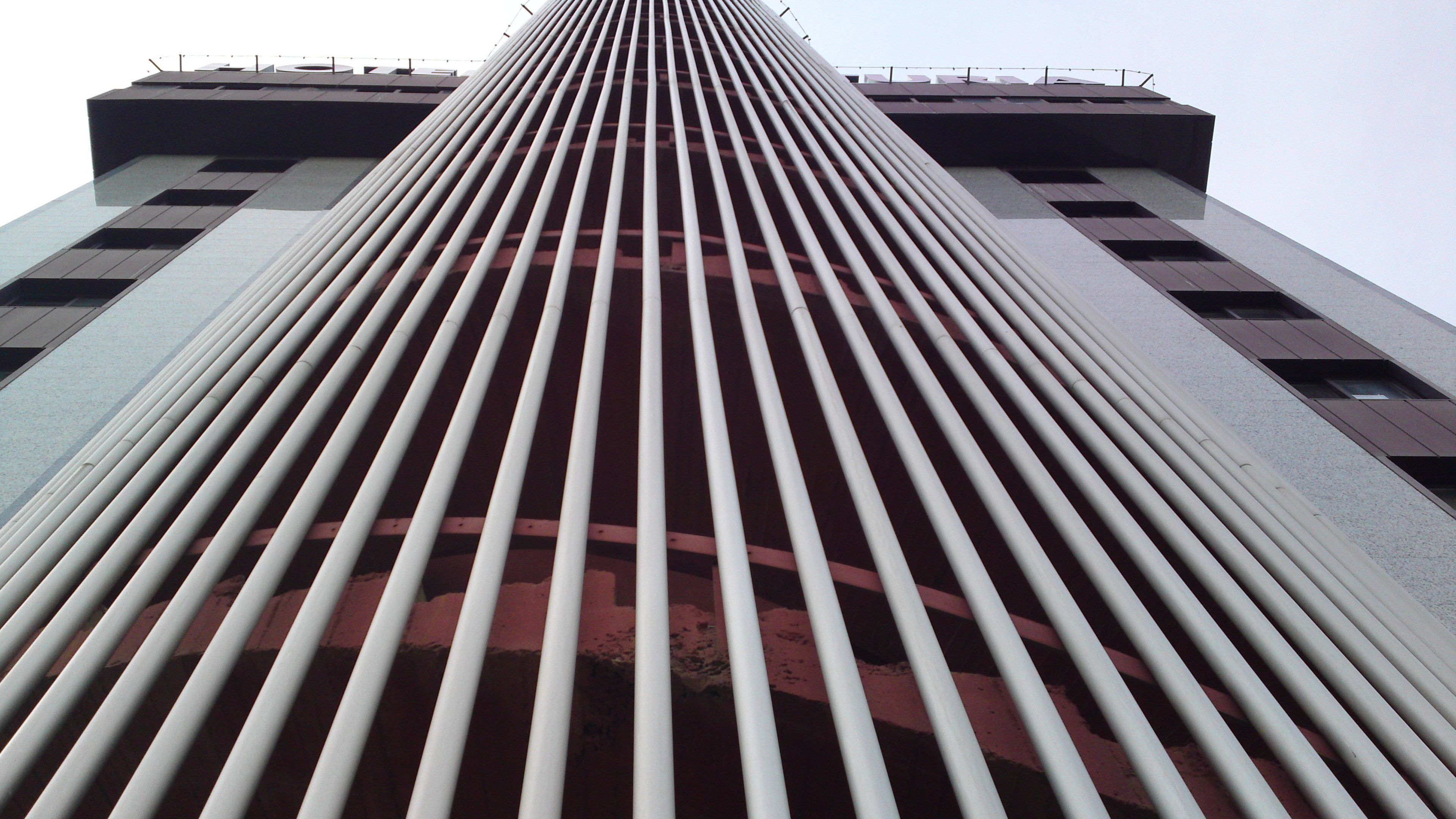 Un immeuble imposant, doté d’une architecture moderne, caractérisé par une série de lignes verticales et de fenêtres rectangulaires.