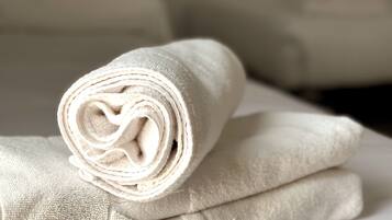 A stack of neatly folded white towels on a bed.