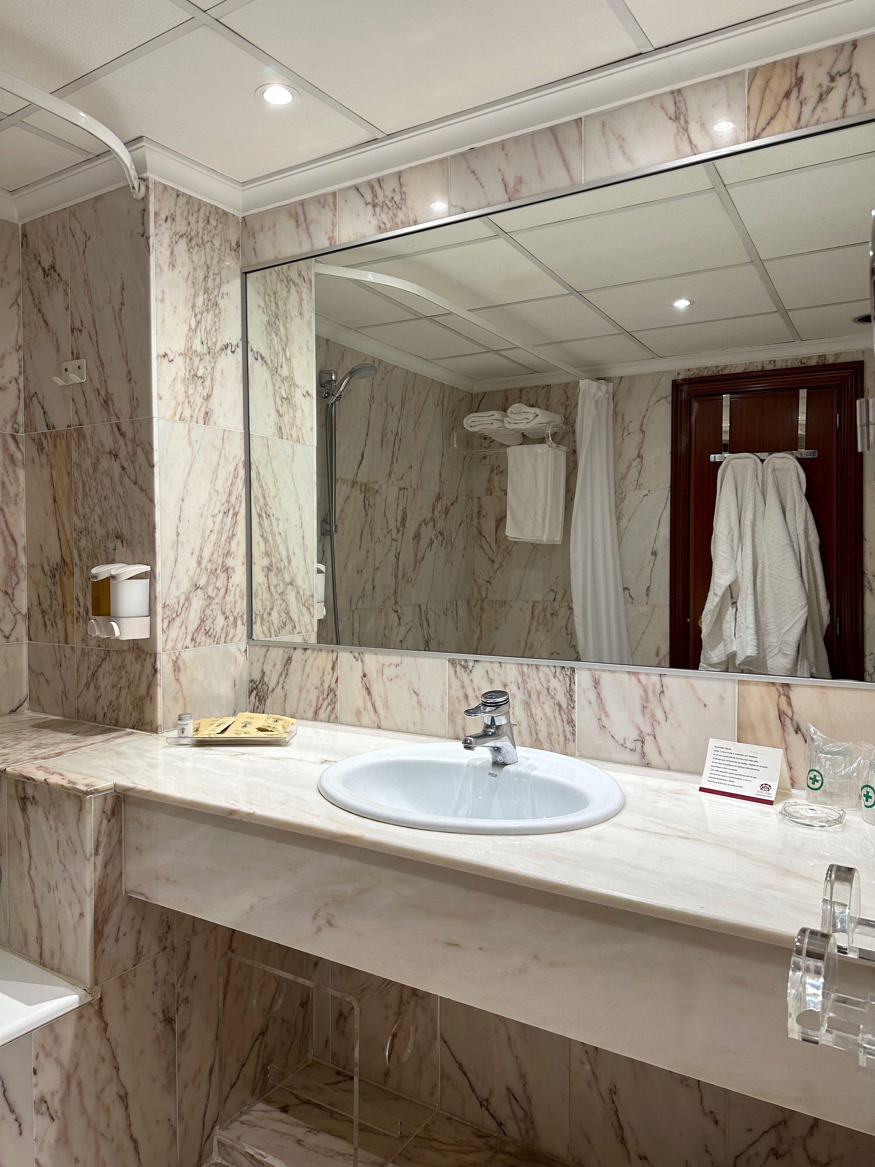 Un baño con tocador de mármol, lavamanos, espejo y zona de ducha.