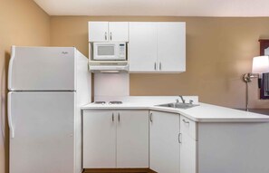 A compact kitchen with white cabinetry, a built-in microwave, a refrigerator, and a sink. - Extended Stay America Suites San Jose Edenvale North (San Jose)