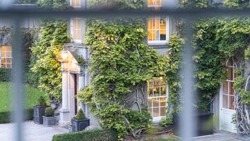 A building with ivy-covered walls, a well-maintained garden, and a classical entrance.