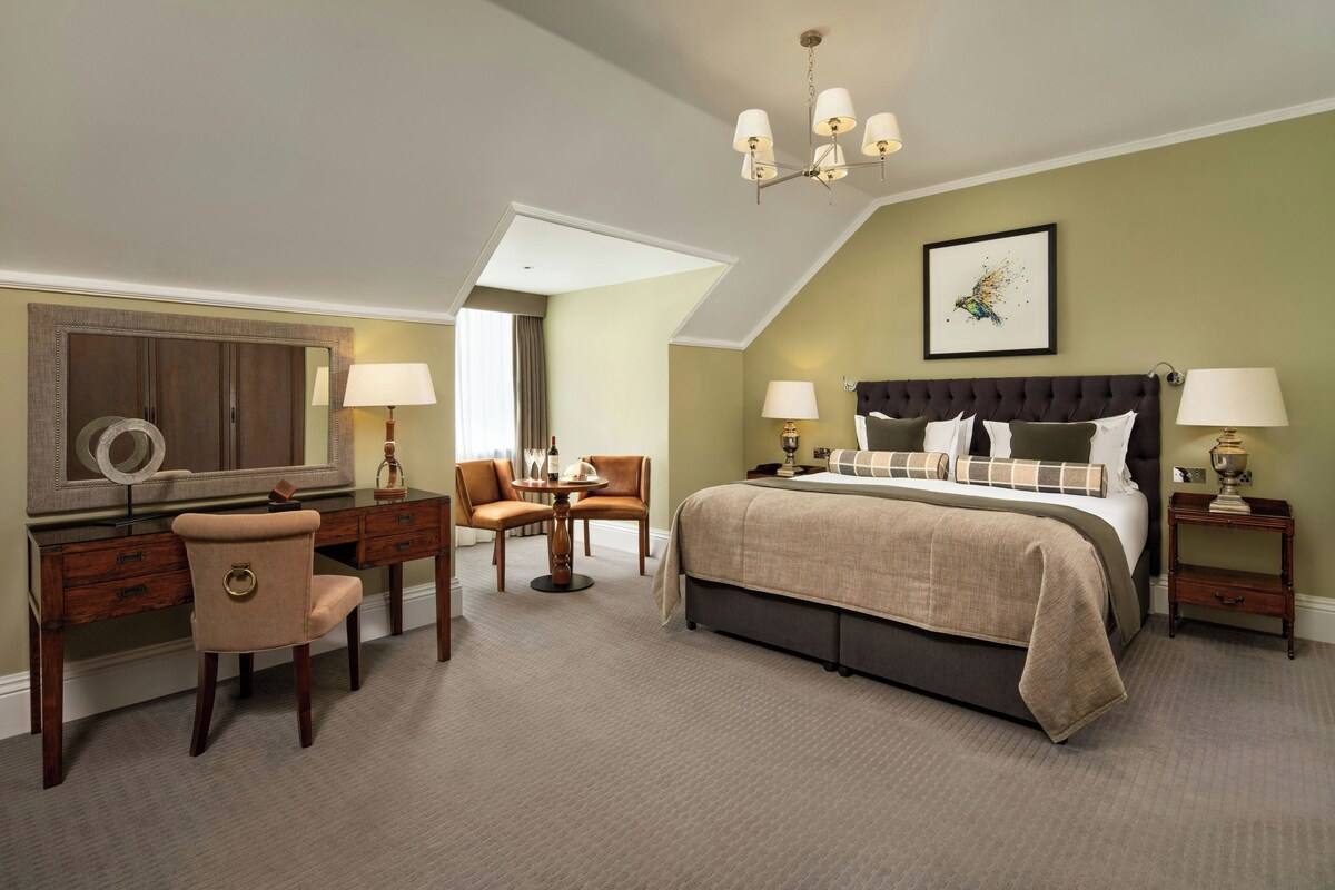 A bedroom with a bed, a desk, a chair, a dresser, and a bedside table.
