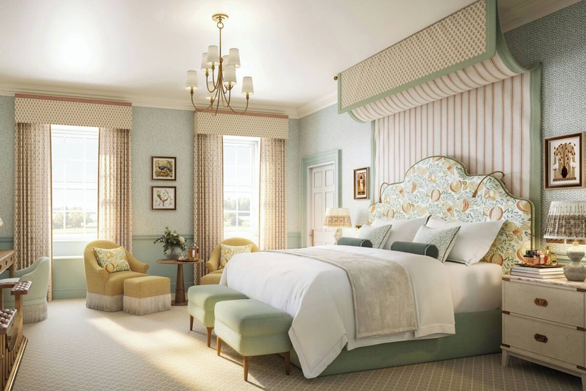 A bedroom with a large bed, two armchairs, a small table, and a nightstand.