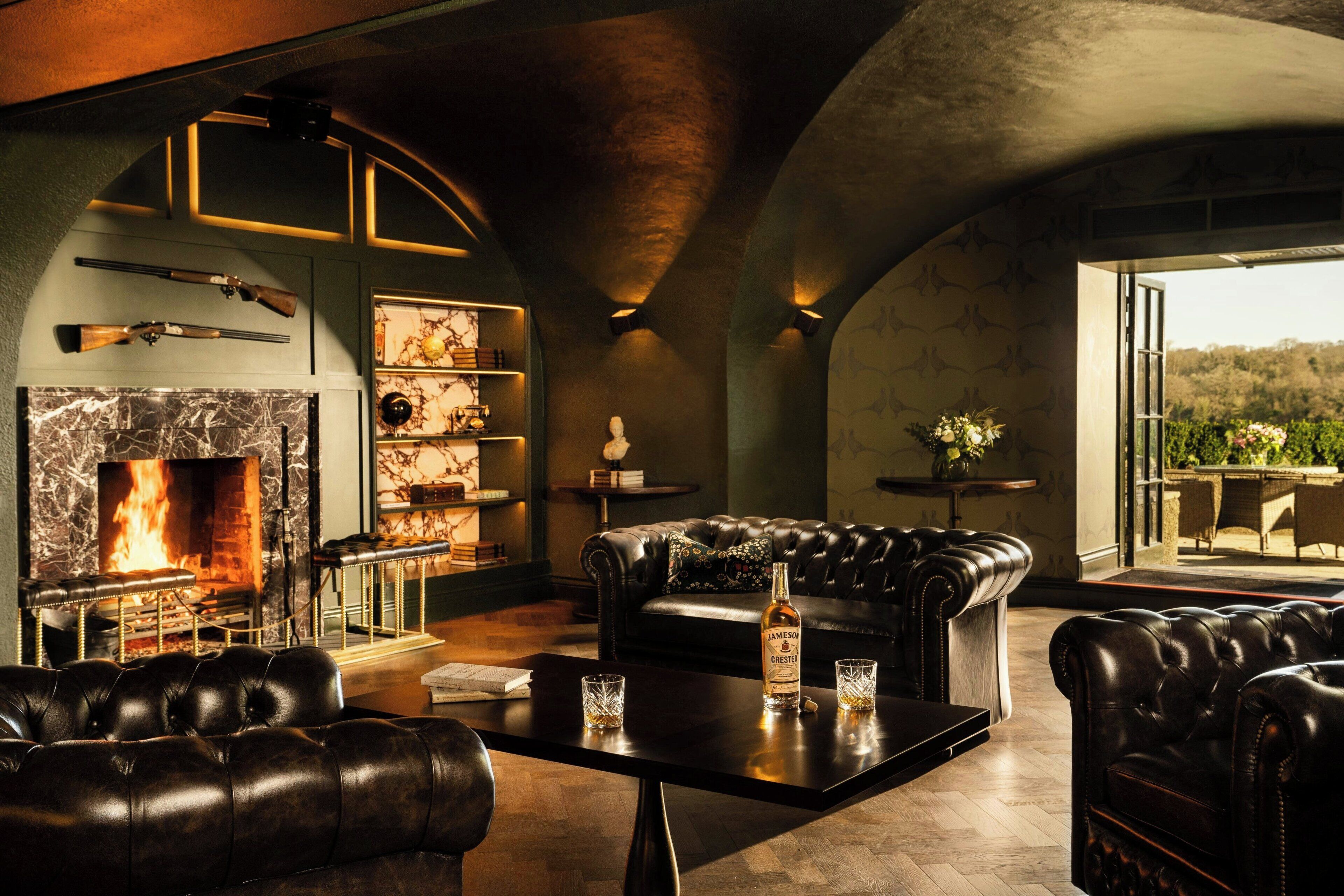 Un salon luxueux avec des canapés en cuir, une cheminée et une vue sur l’extérieur.